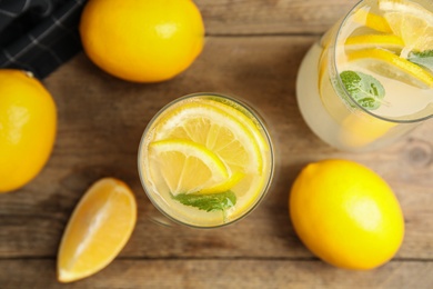 Cool freshly made lemonade and fruits on wooden table, flat lay