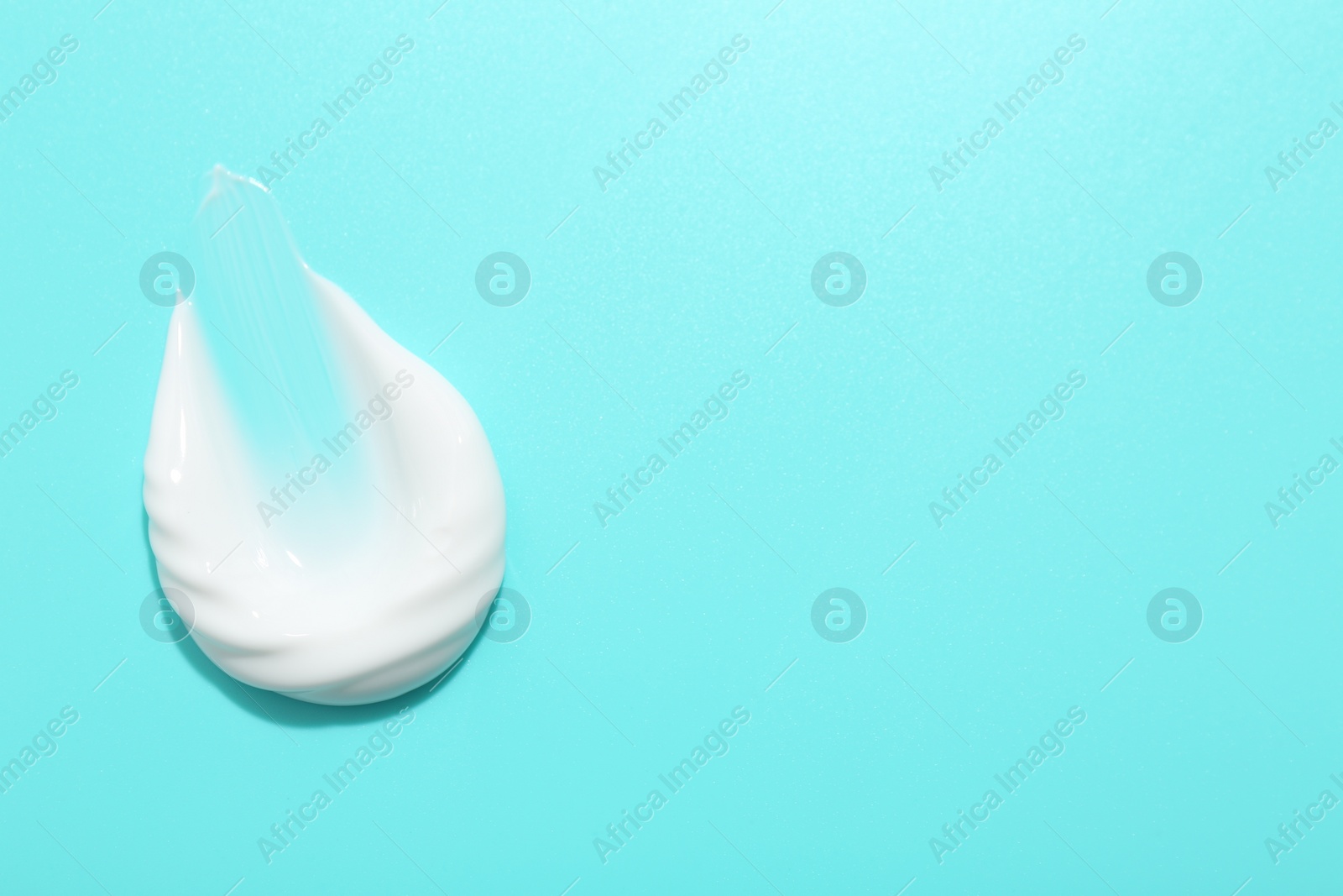 Photo of Sample of face cream on light blue background, top view. Space for text