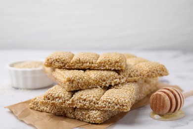 Delicious sesame kozinaki bars and wooden dipper on white table, closeup