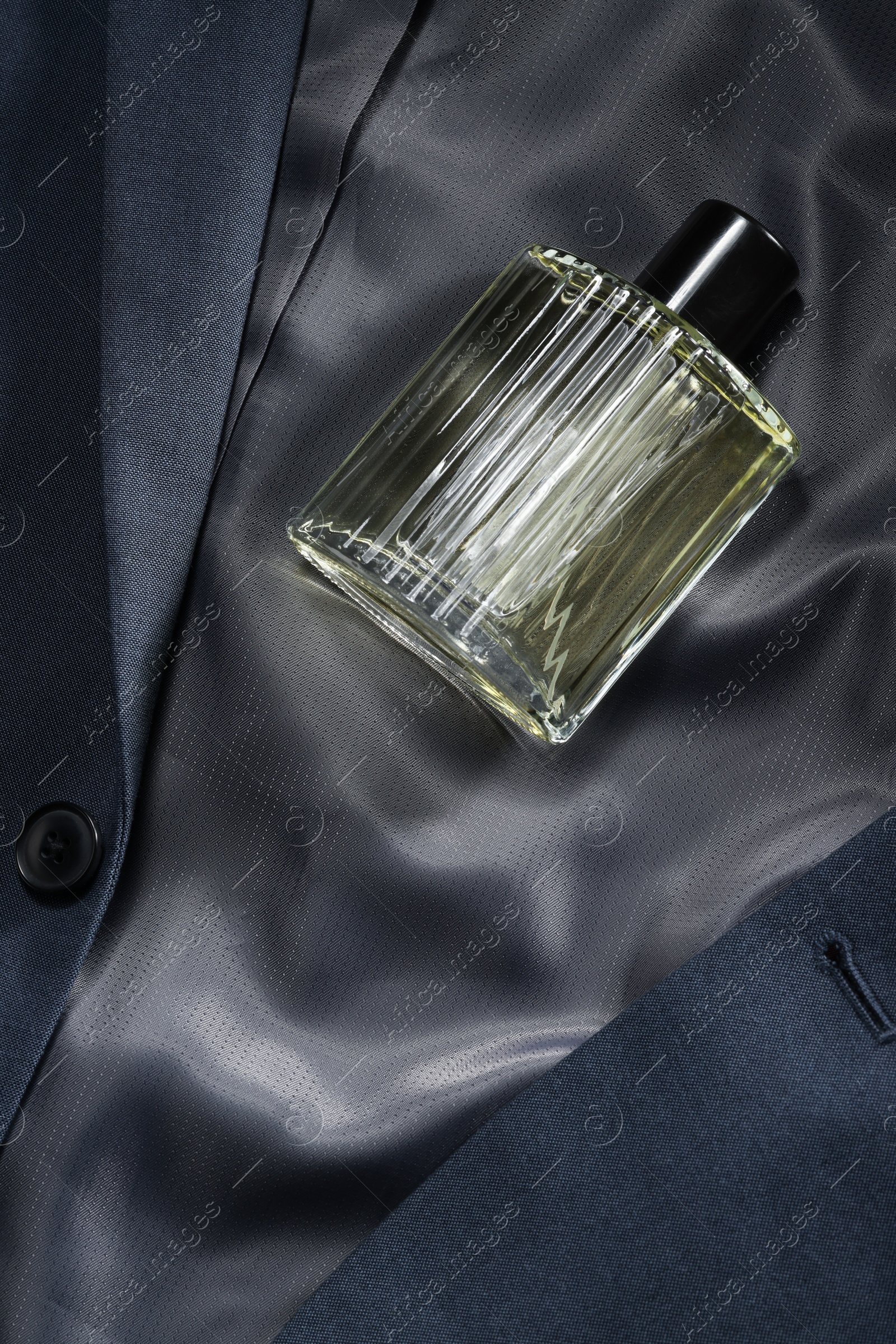 Photo of Luxury men's perfume in bottle on grey jacket, top view. Space for text