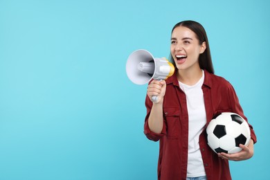 Photo of Happy fan with soccer ball using megaphone on light blue background, space for text