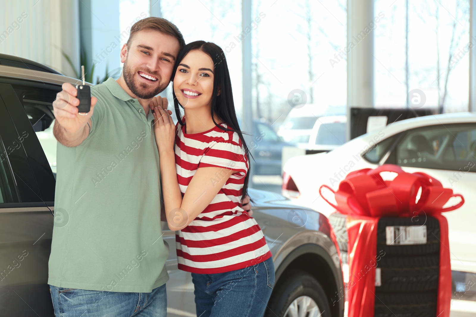 Photo of Happy couple with car key in modern auto dealership