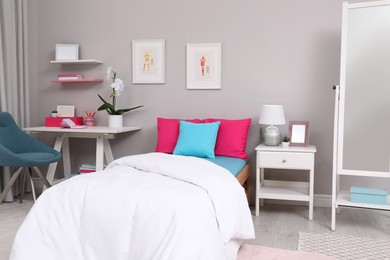 Modern teenager's room interior with comfortable bed and workplace