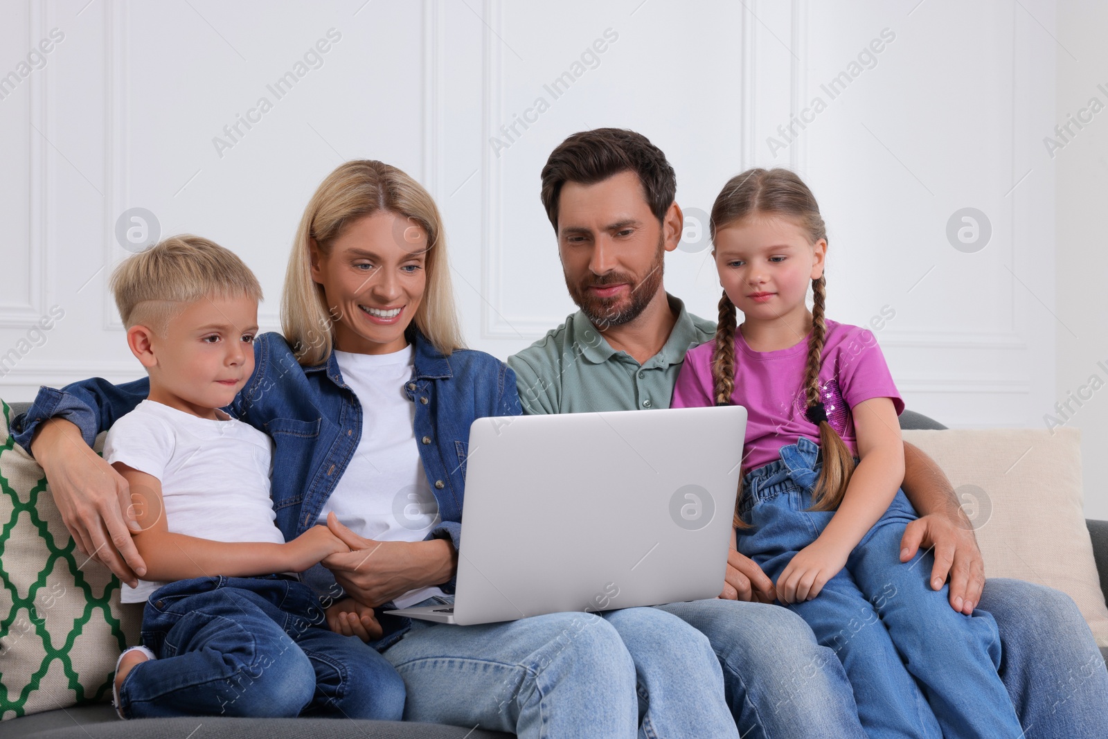 Photo of Happy family with laptop spending time together on sofa at home