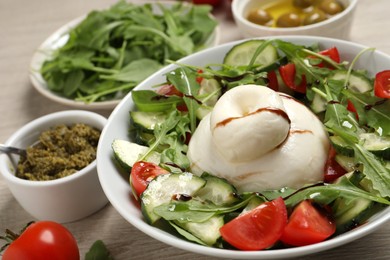 Photo of Delicious burrata salad and ingredients on wooden table