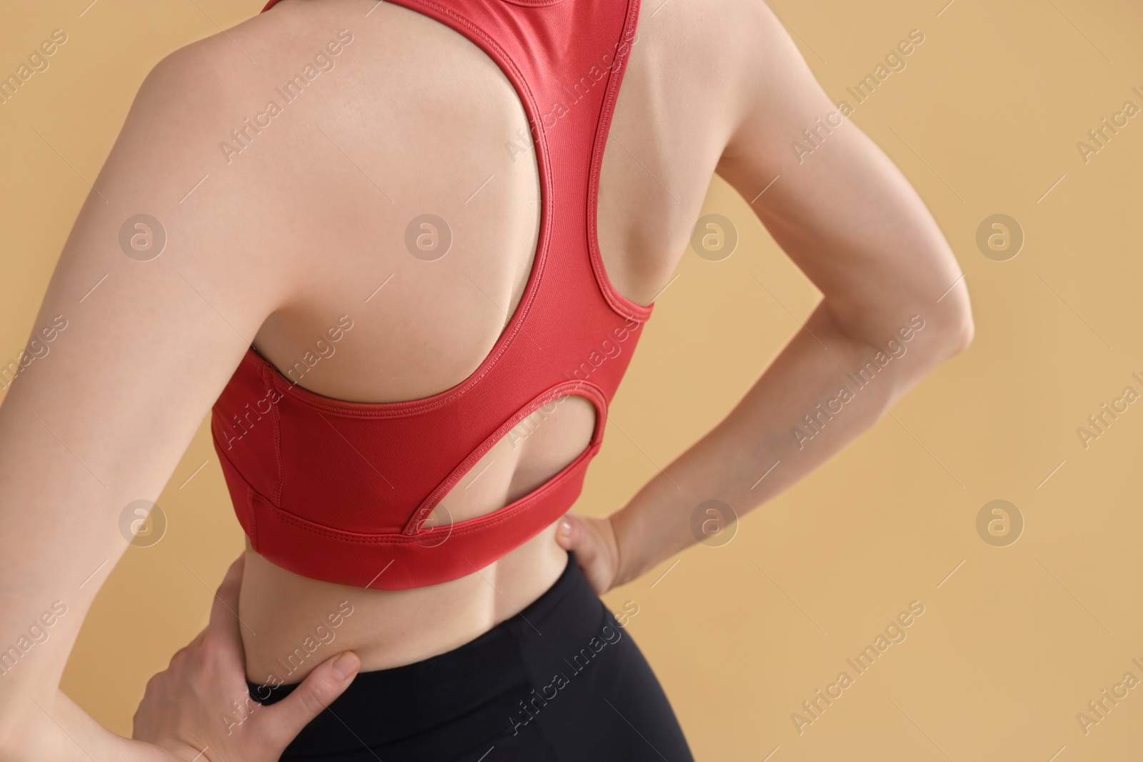 Photo of Young woman in sportswear on beige background, back view. Space for text