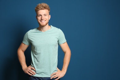 Photo of Young man wearing blank t-shirt on blue background. Mockup for design