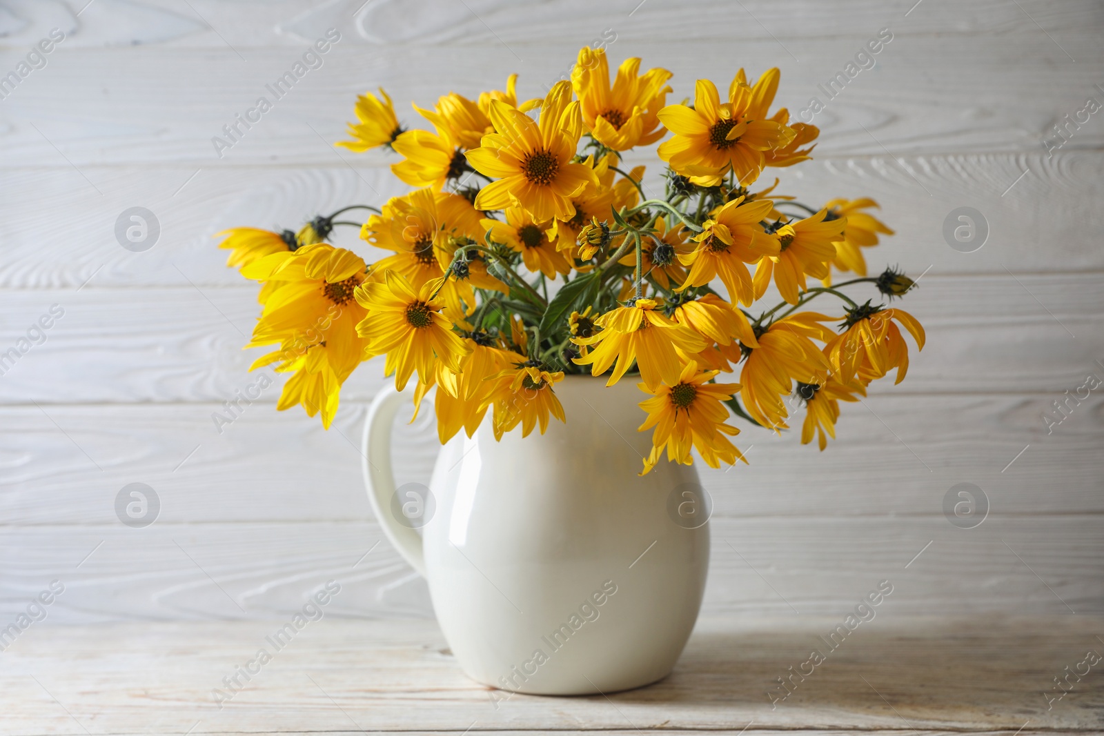 Photo of Beautiful yellow flowers on light wooden table