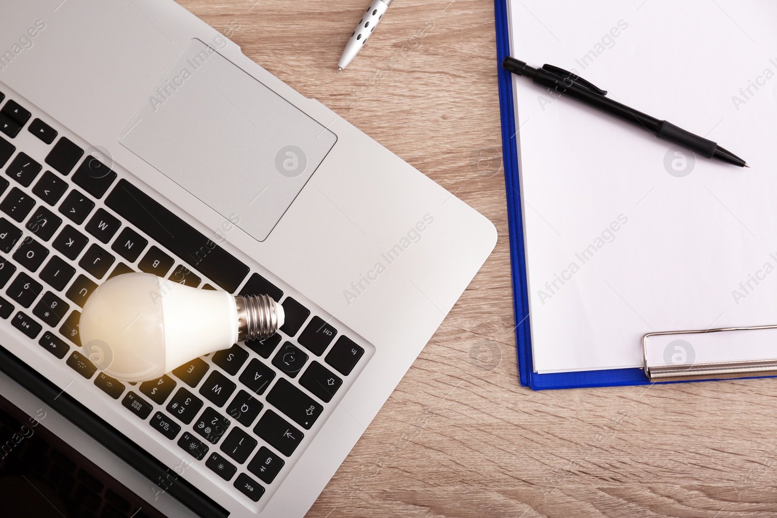 Photo of Flat lay composition with laptop and lamp bulb on wooden background