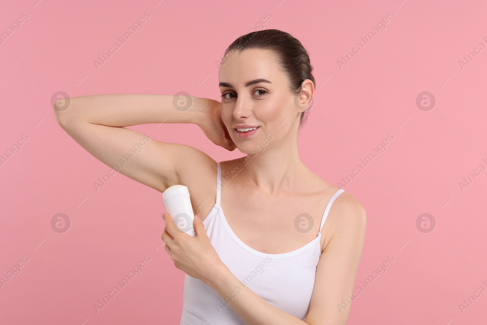 Photo of Beautiful woman applying deodorant on pink background