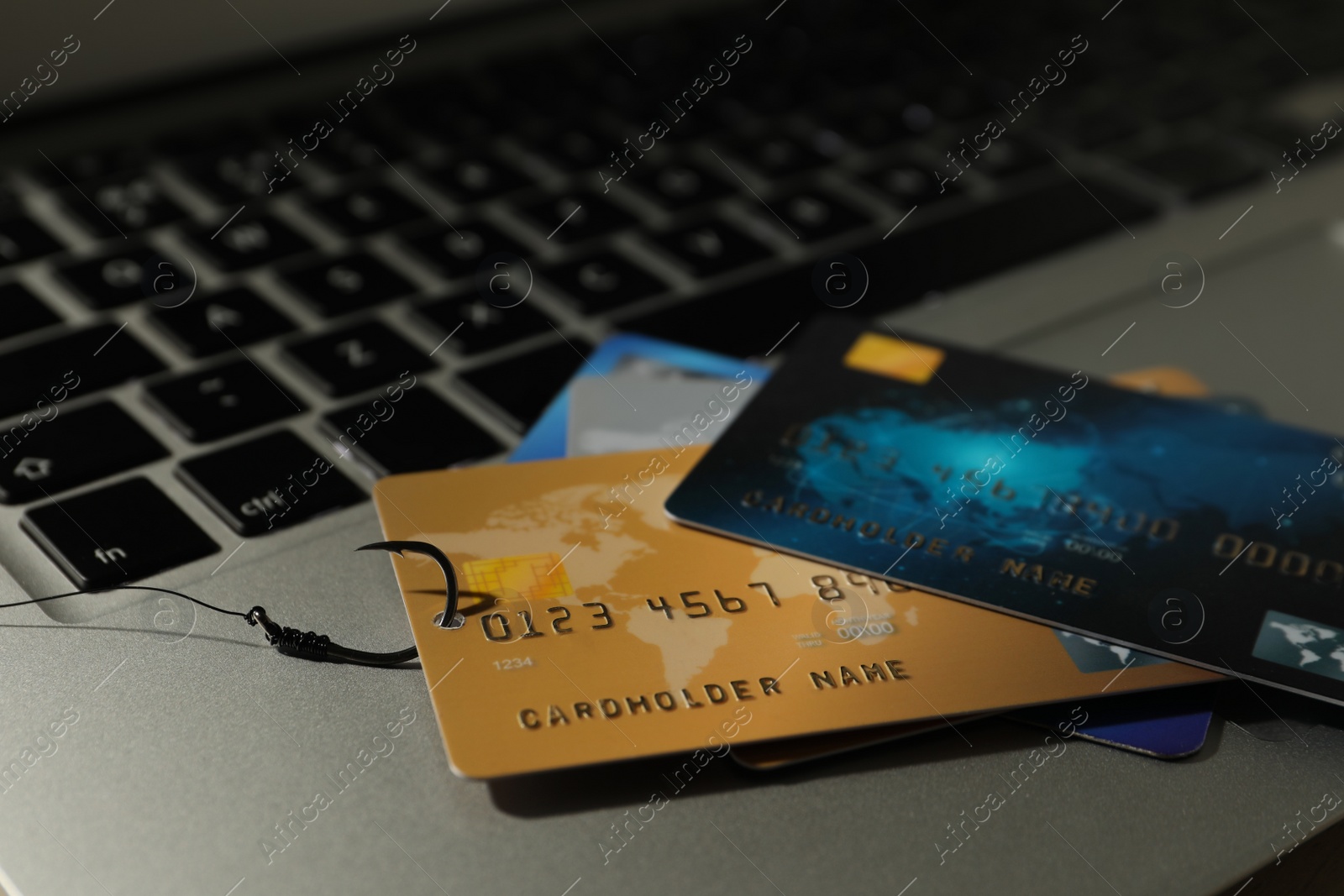 Photo of Fishing hook with credit cards on laptop, closeup. Cyber crime