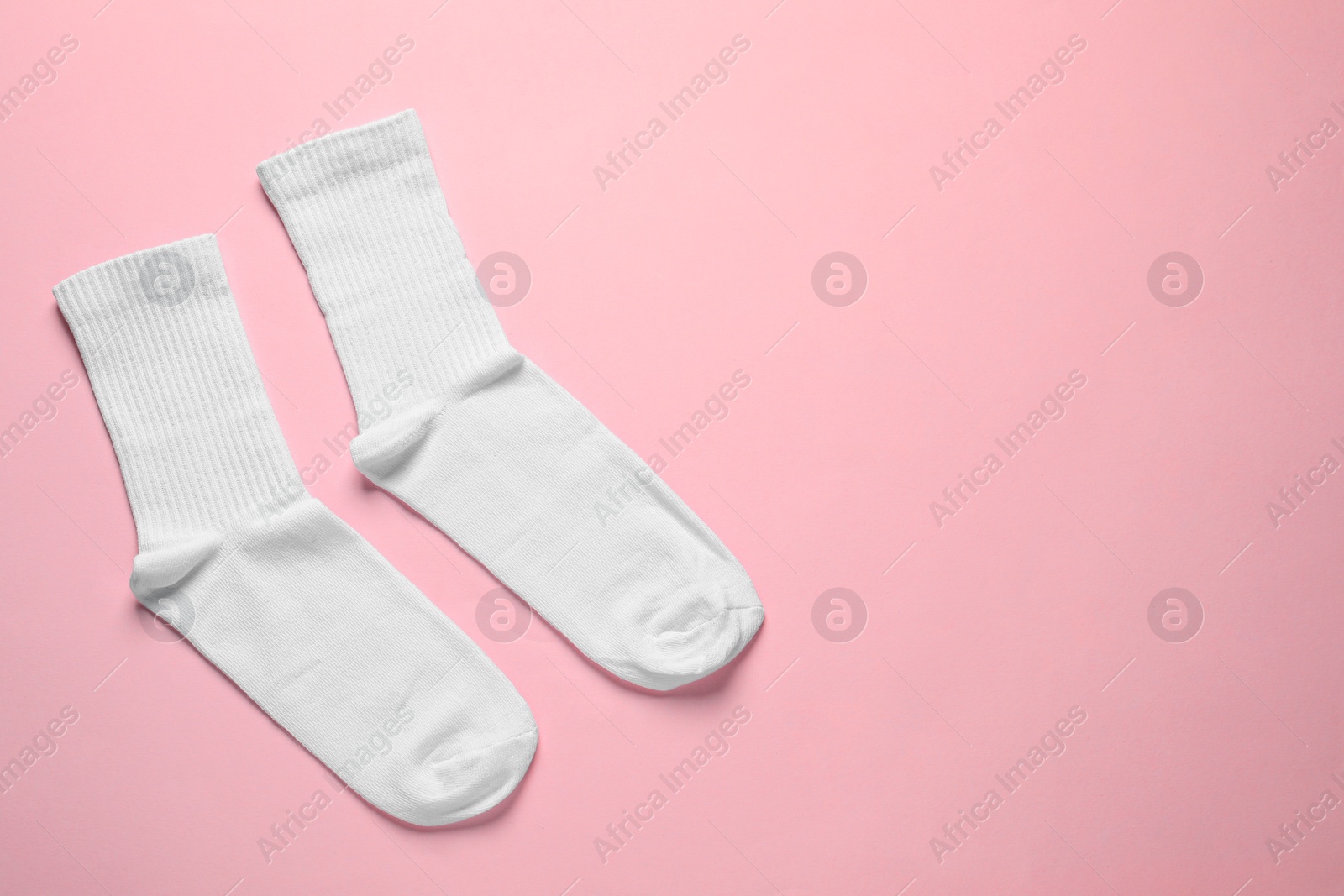 Photo of Pair of white socks on pink background, flat lay. Space for text