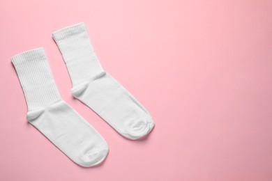 Pair of white socks on pink background, flat lay. Space for text