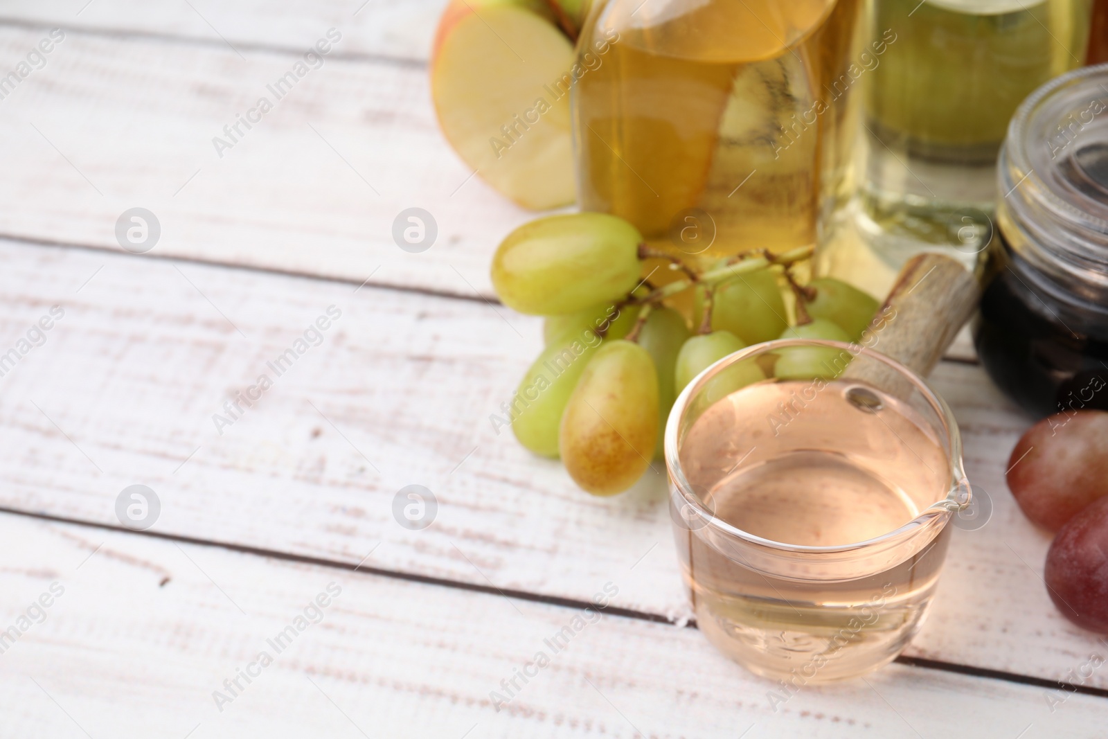 Photo of Different types of vinegar and grapes on wooden table, closeup. Space for text