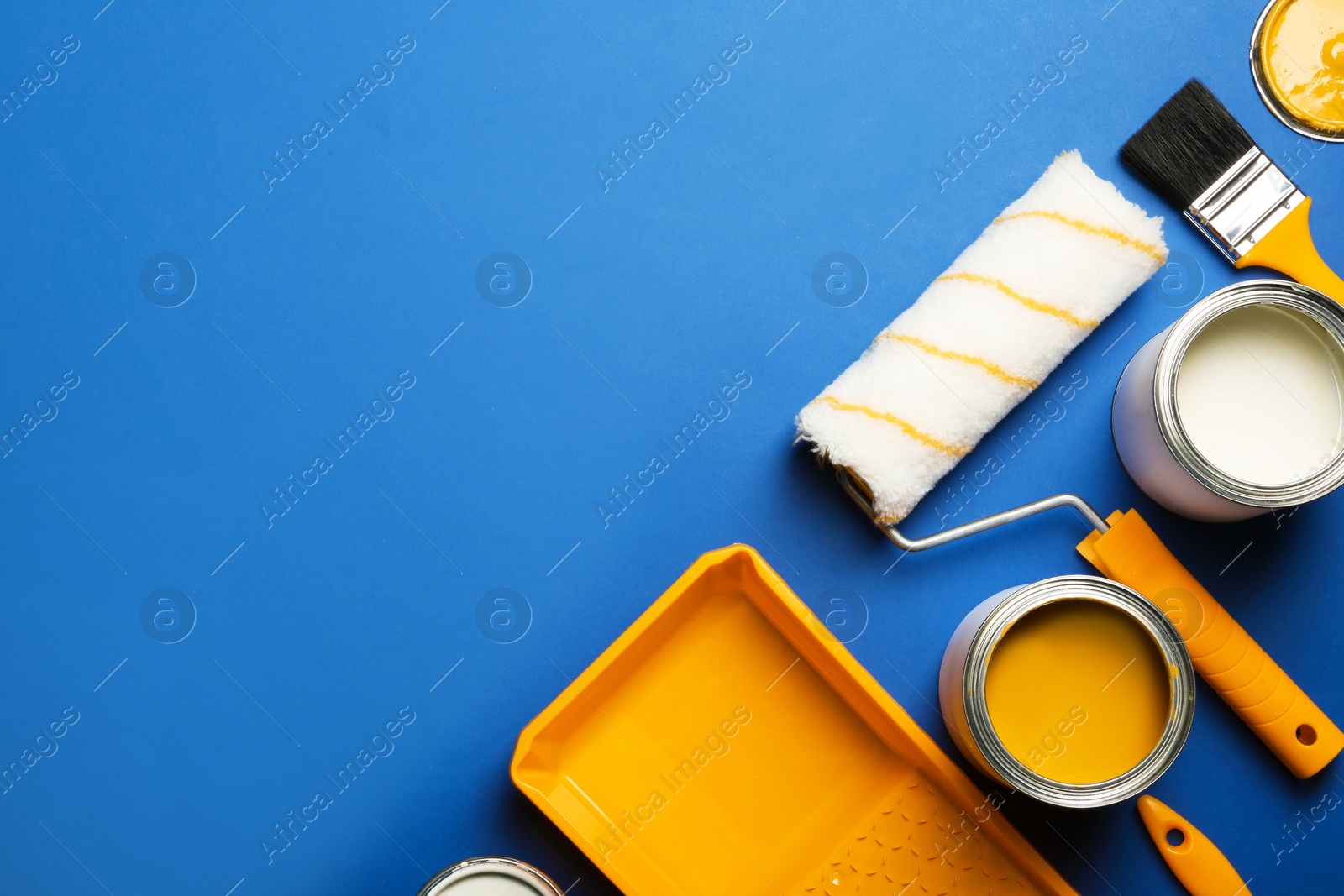 Photo of Flat lay composition with paint cans, decorator tools and space for text on color background