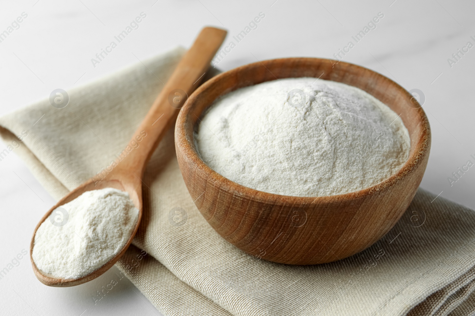 Photo of Bowl and spoon of agar-agar powder on white table, closeup