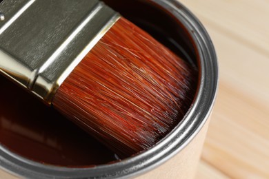 Photo of Dipping brush into can with wood stain on table, closeup