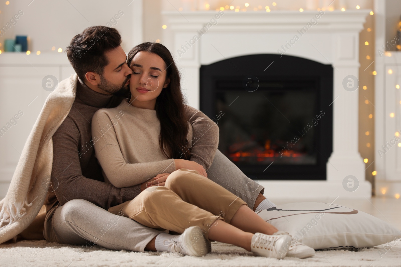 Photo of Young man kissing his girlfriend on soft carpet at home. Space for text