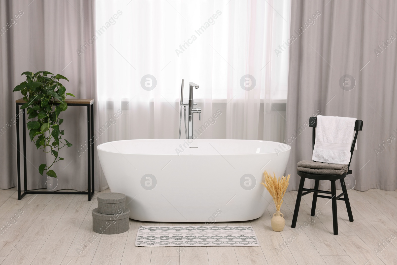 Photo of Stylish bathroom interior with soft bath mat and tub