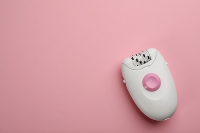Modern epilator on pink background, top view. Space for text