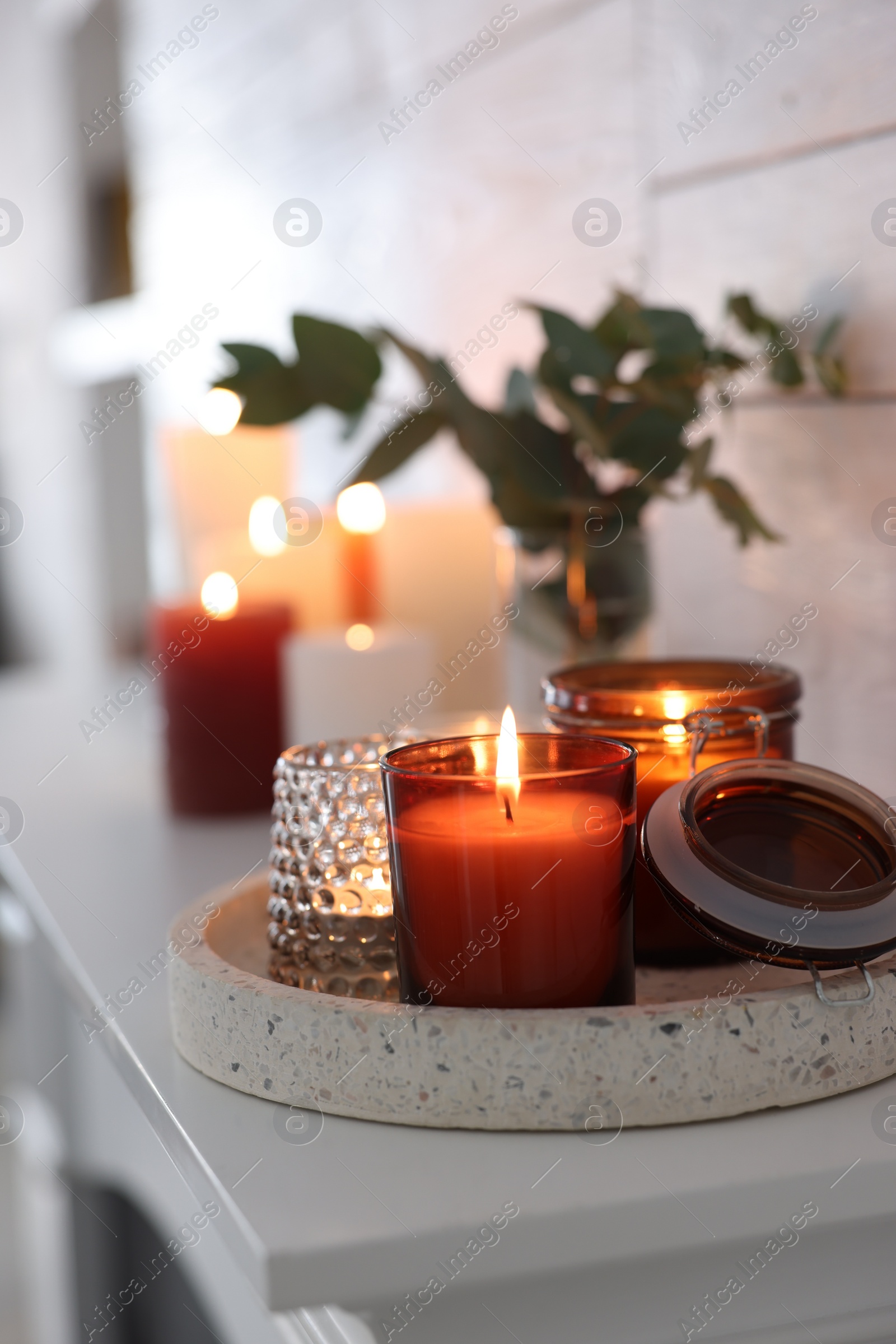 Photo of Burning candles on mantel near white wall indoors