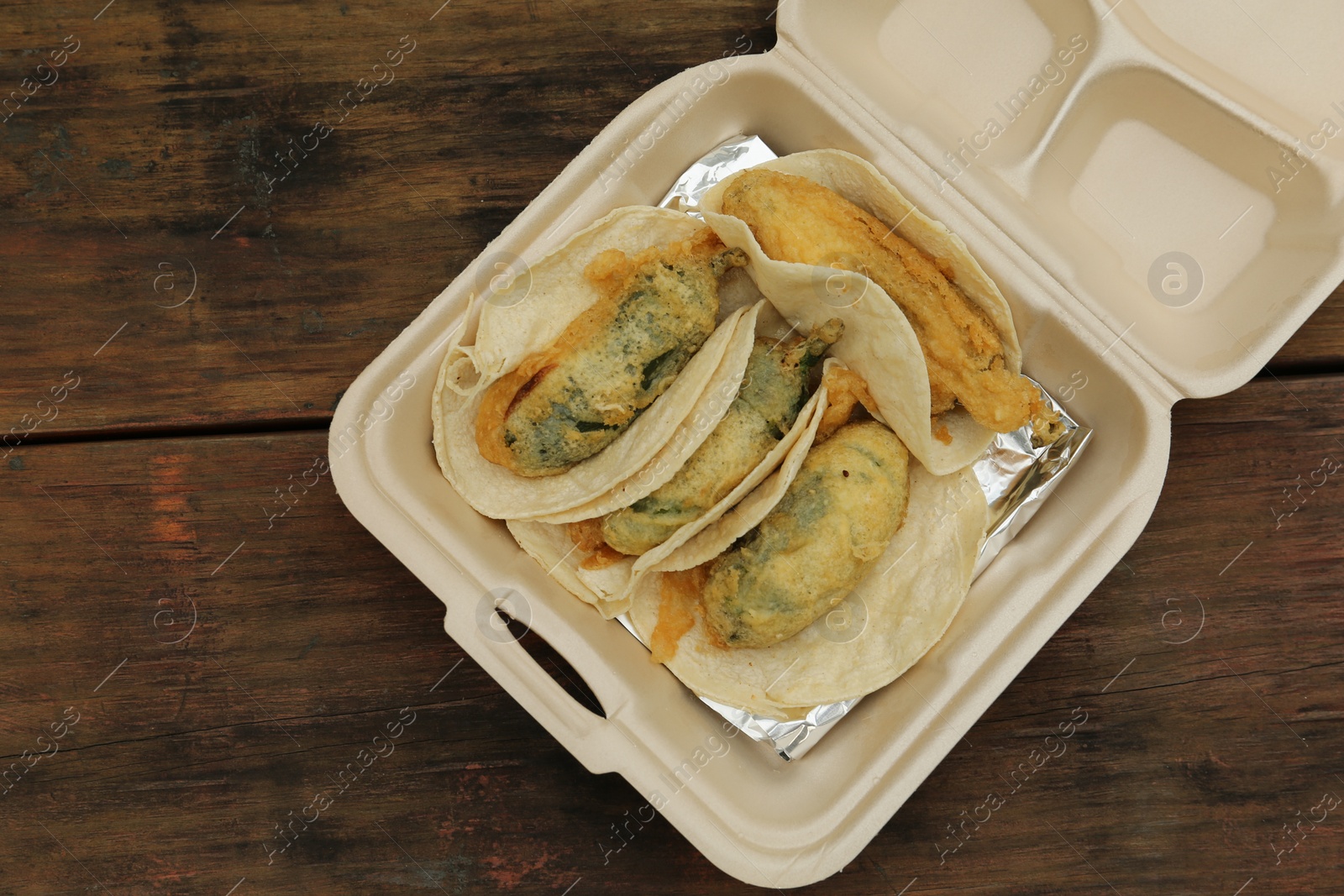 Photo of Jalapeno peppers stuffed with cheese in box on wooden table, top view