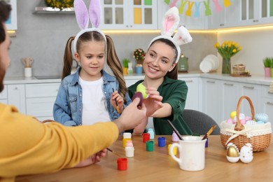 Family painting Easter eggs at table in kitchen