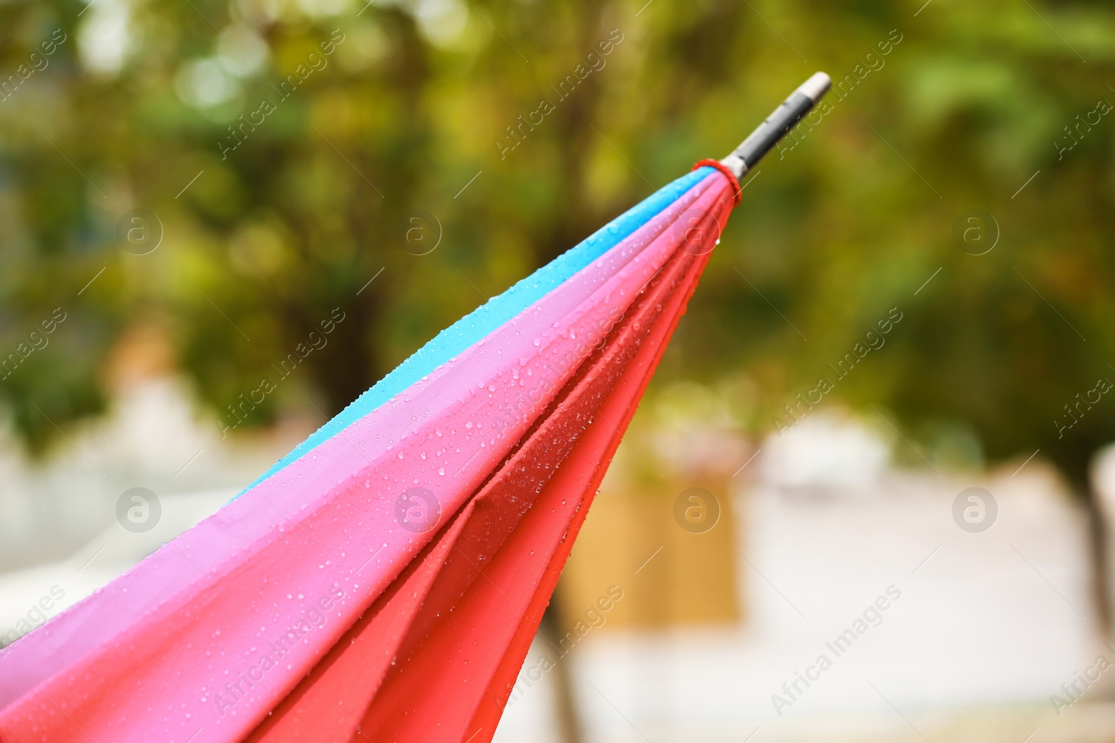 Photo of Bright folded umbrella under rain on street, closeup