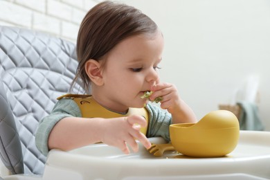 Photo of Cute little baby eating healthy food in high chair indoors