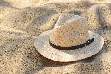 Photo of Stylish straw hat on sand outdoors. Beach accessory