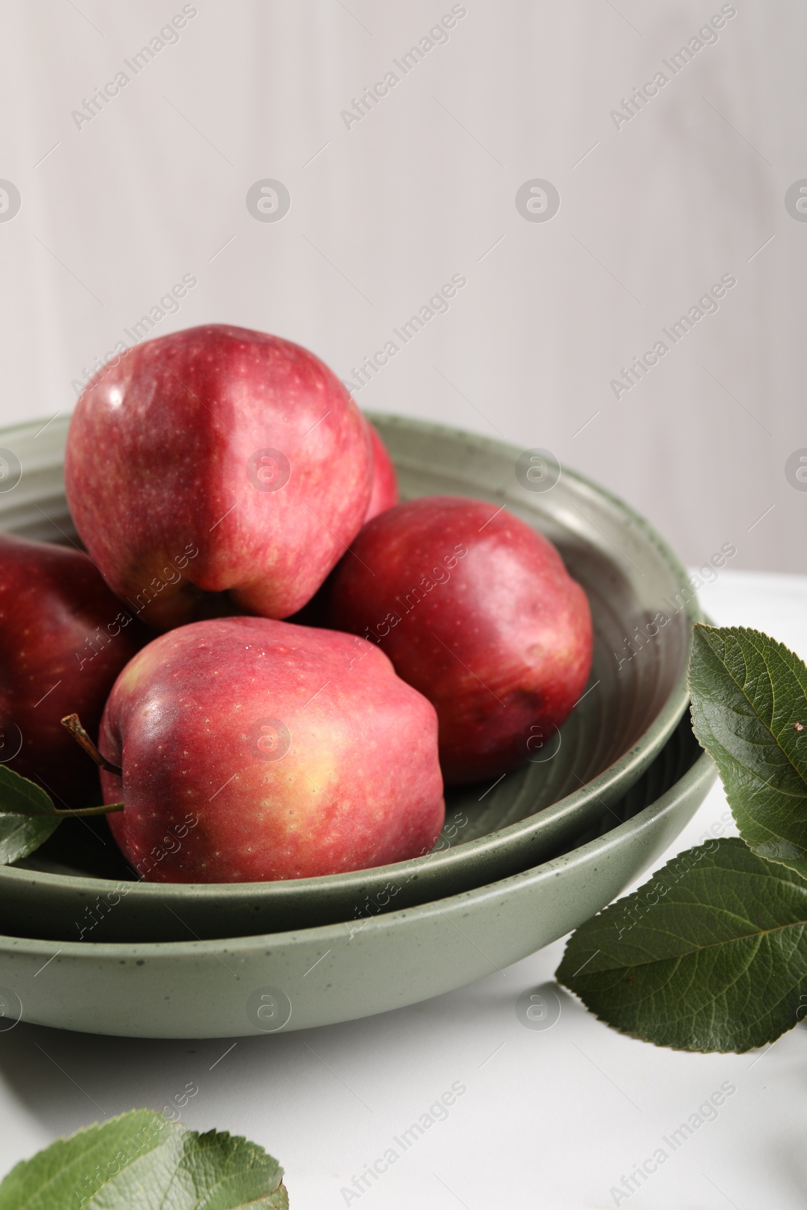 Photo of Fresh red apples and leaves on white table