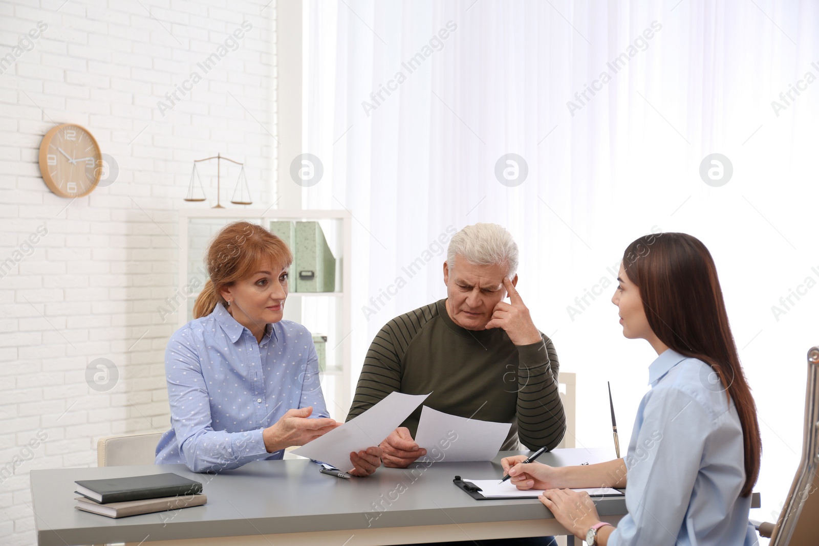 Photo of Young lawyer consulting senior couple in office