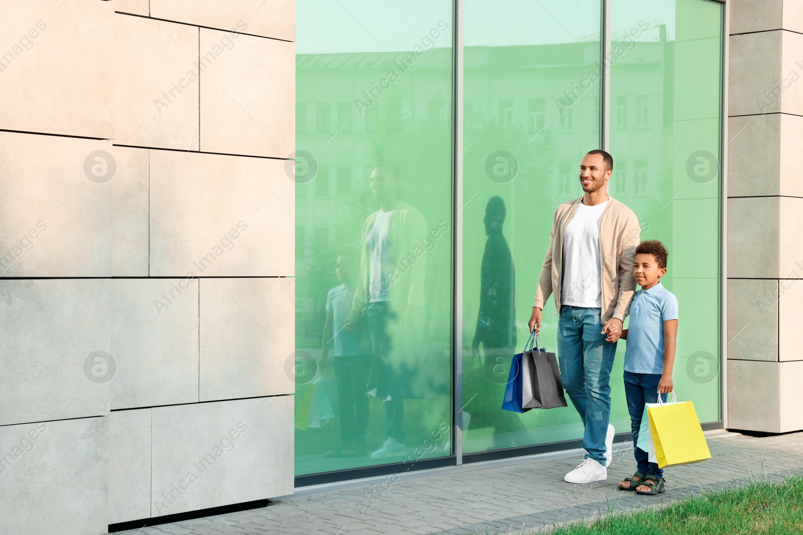 Photo of Family shopping. Happy father and son with colorful bags near mall outdoors