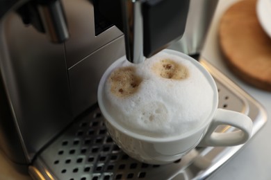 Photo of Modern coffee machine with cup of cappuccino, closeup