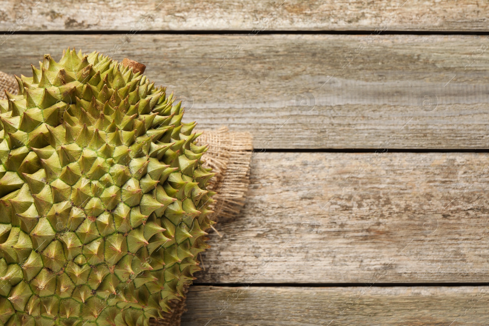 Photo of Ripe durian on wooden table, top view. Space for text