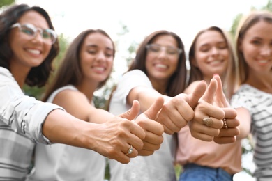 Happy women showing thumbs up outdoors, focus of hands. Girl power concept