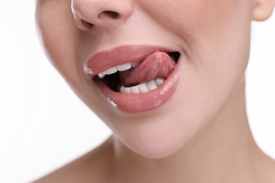 Woman with beautiful lips licking her teeth on white background, closeup