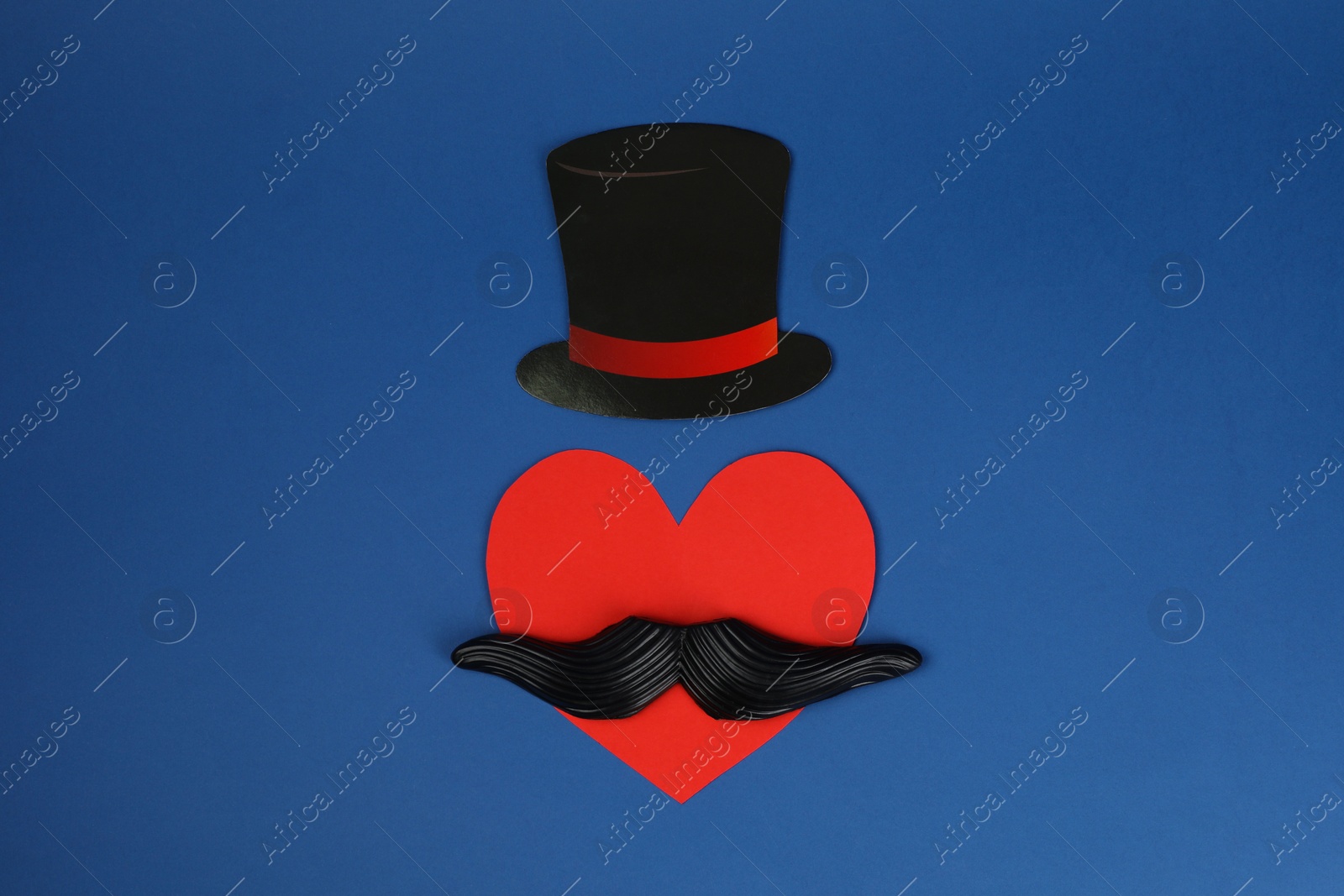 Photo of Fake mustache, paper hat and heart on blue background, top view