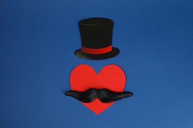 Photo of Fake mustache, paper hat and heart on blue background, top view