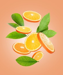 Image of Juicy orange slices and green leaves flying on peach background