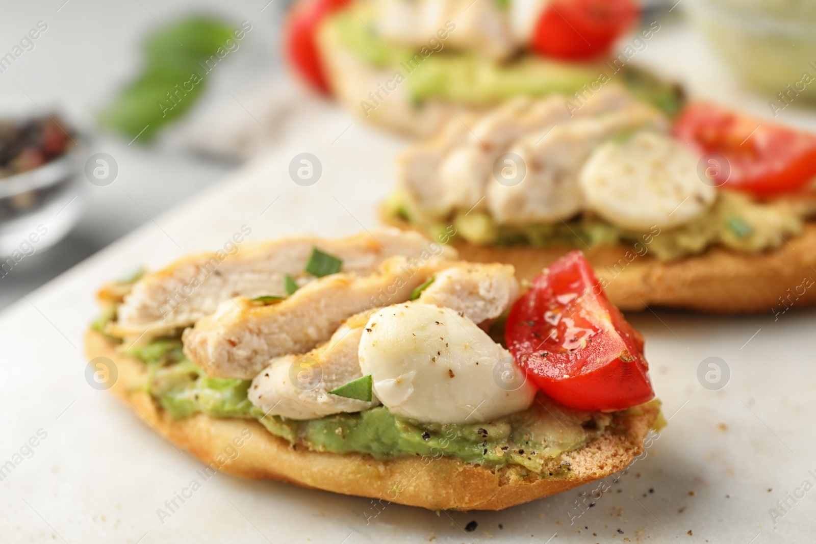 Photo of Board with delicious chicken bruschettas on table, closeup