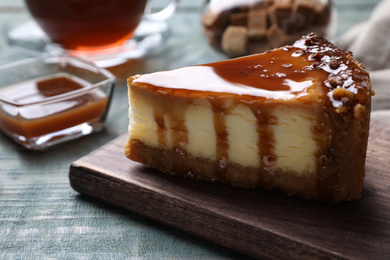 Piece of delicious cake with caramel served on blue wooden table, closeup