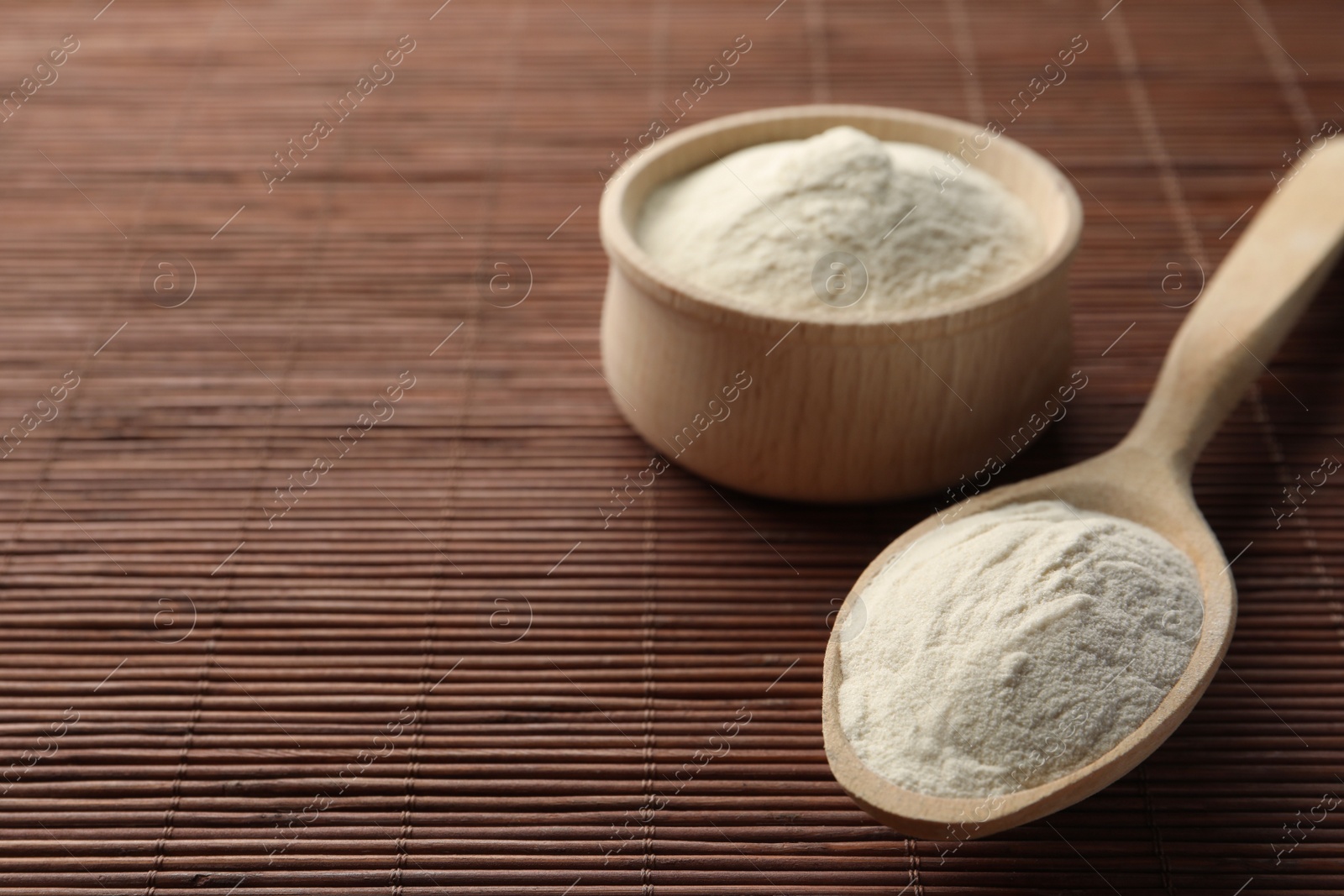 Photo of Bowl and spoon of agar-agar powder on bamboo mat, closeup. Space for text