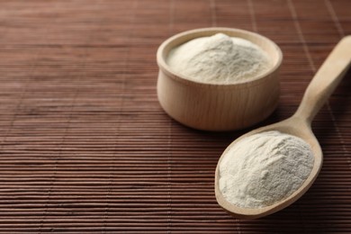 Photo of Bowl and spoon of agar-agar powder on bamboo mat, closeup. Space for text