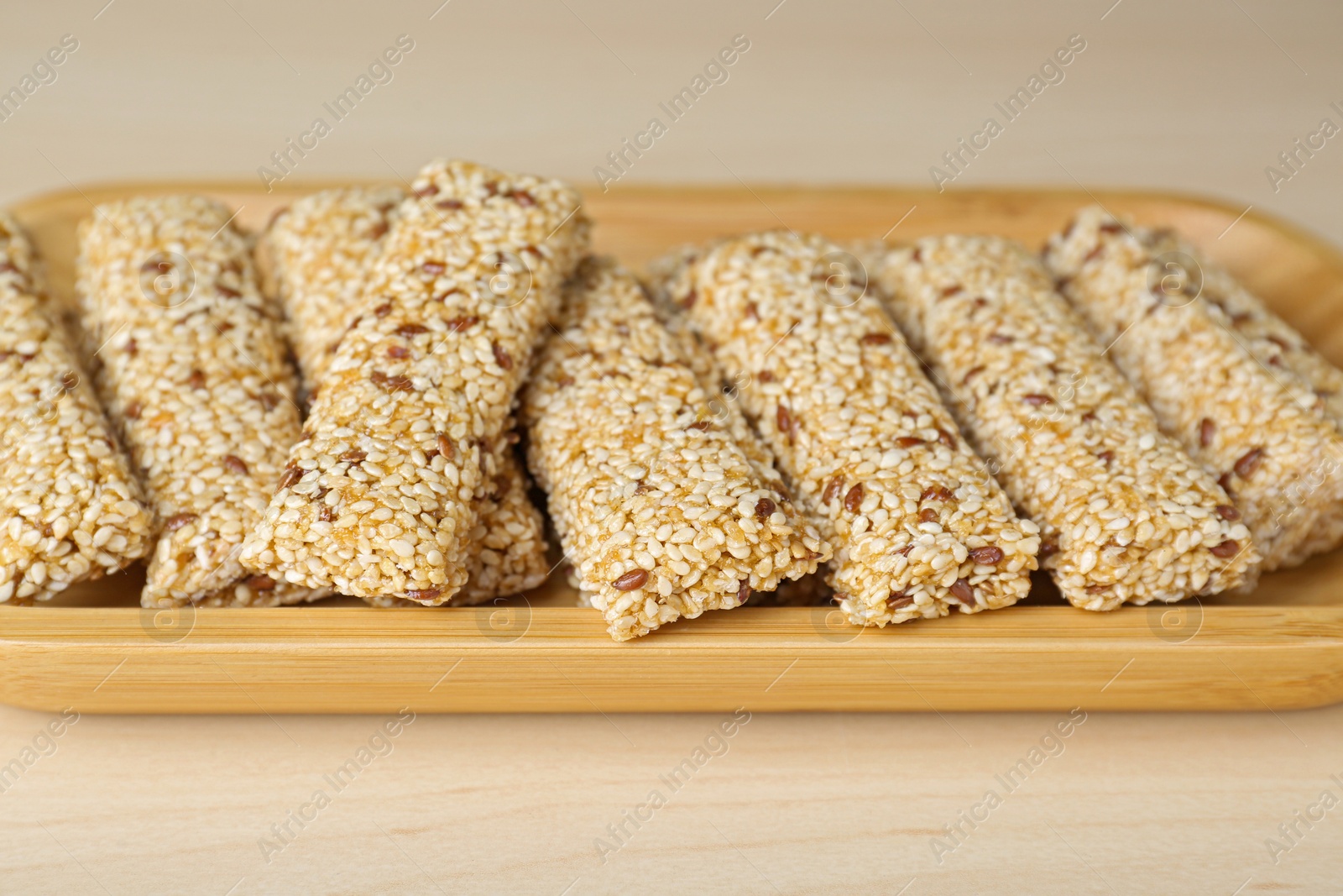 Photo of Plate with tasty sesame seed bars on wooden table, closeup