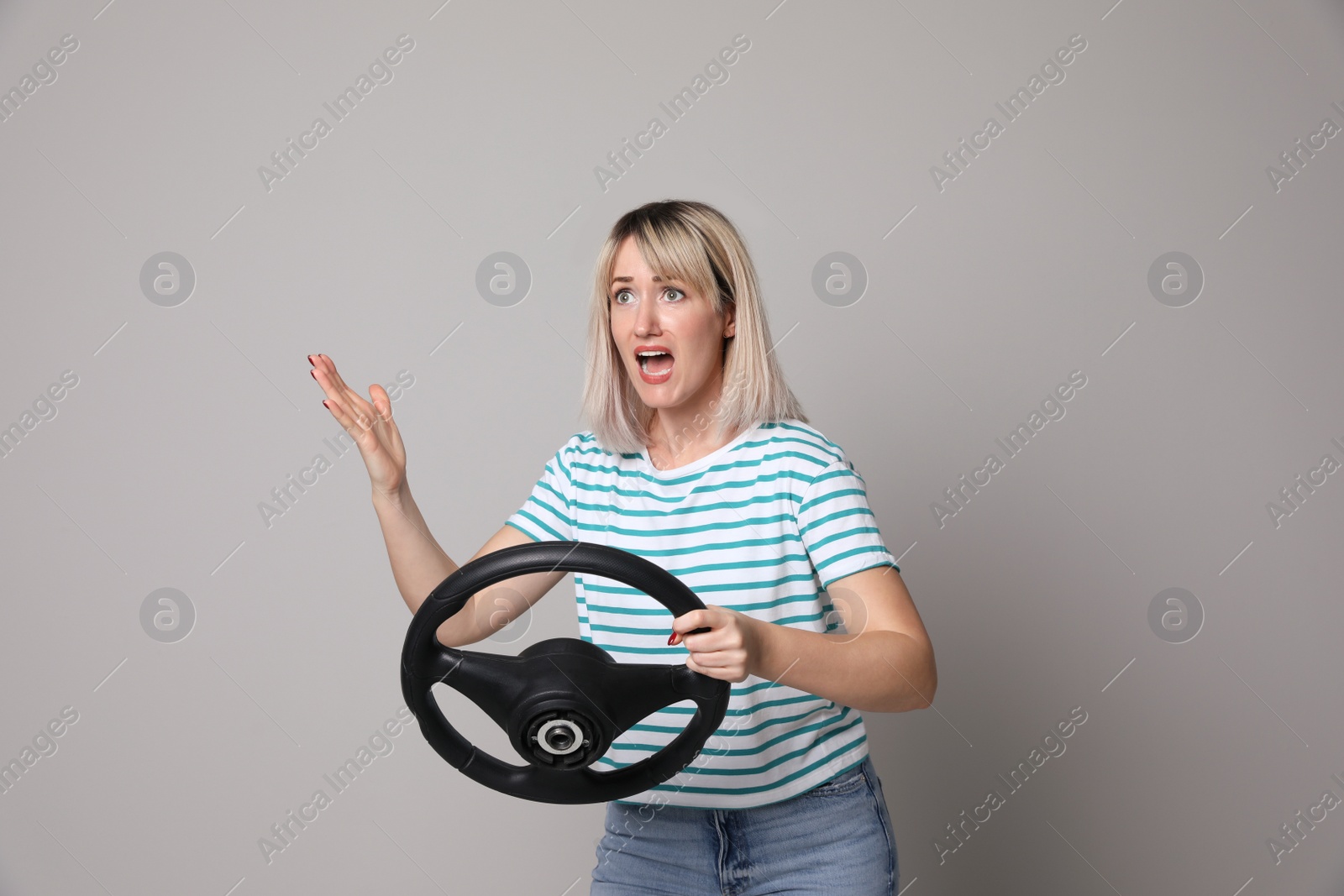 Photo of Emotional woman with steering wheel on grey background