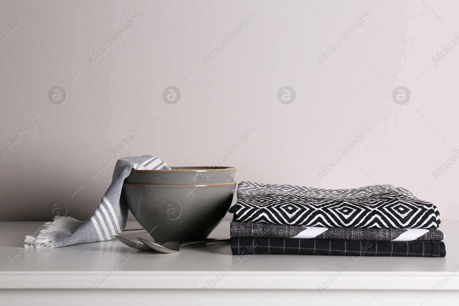 Photo of Kitchen towels and tableware on white countertop near wall