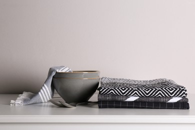 Photo of Kitchen towels and tableware on white countertop near wall