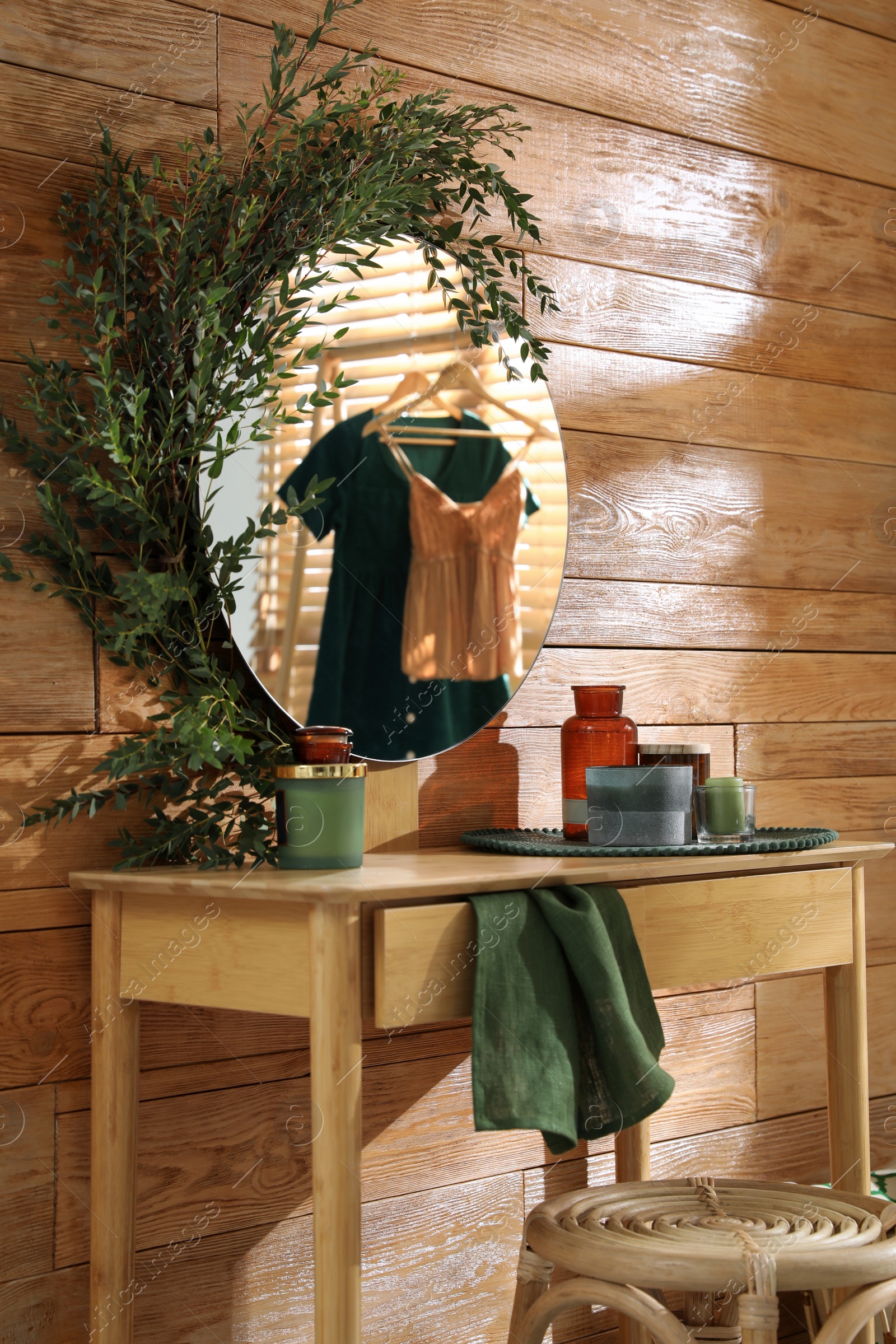 Photo of Stylish dressing table and mirror decorated with green eucalyptus in room