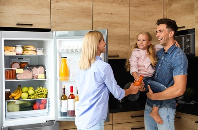 Photo of Happy family with bottle of juice near refrigerator in kitchen